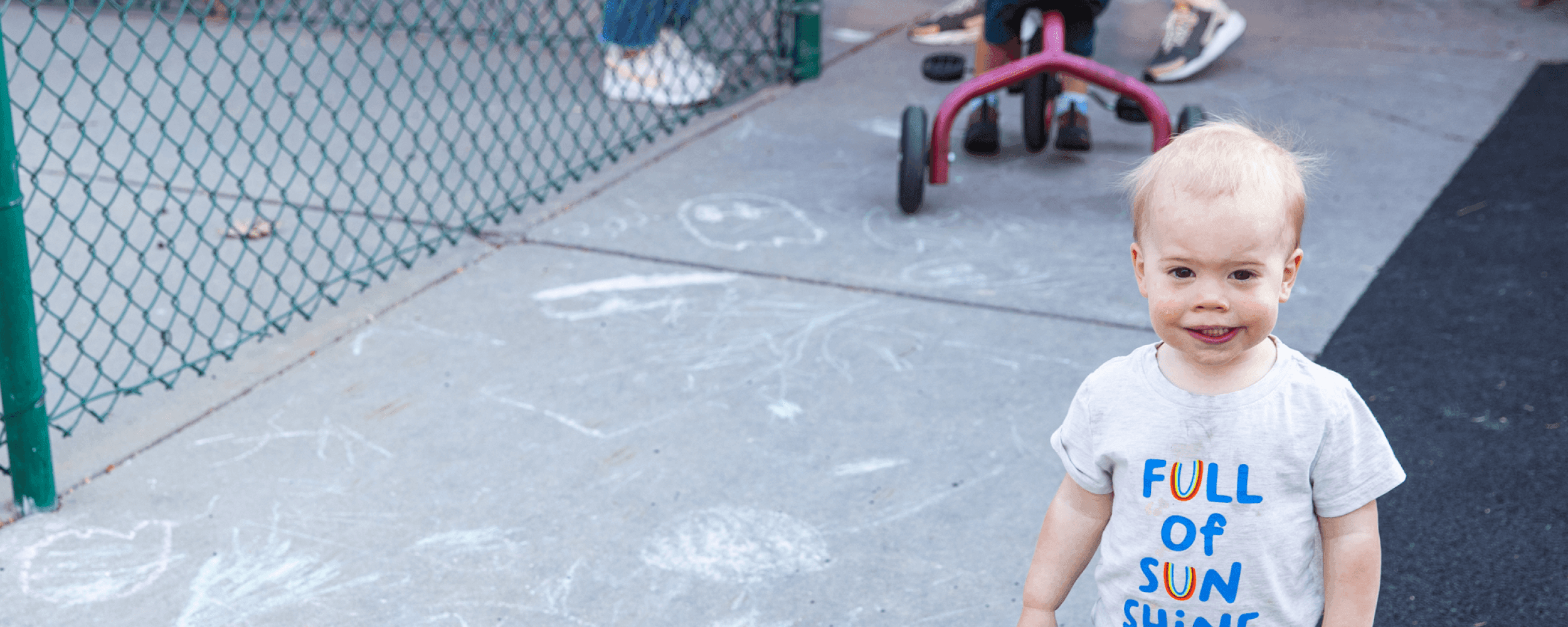 Toddler boy standing outside on the playground and smiling at the camera