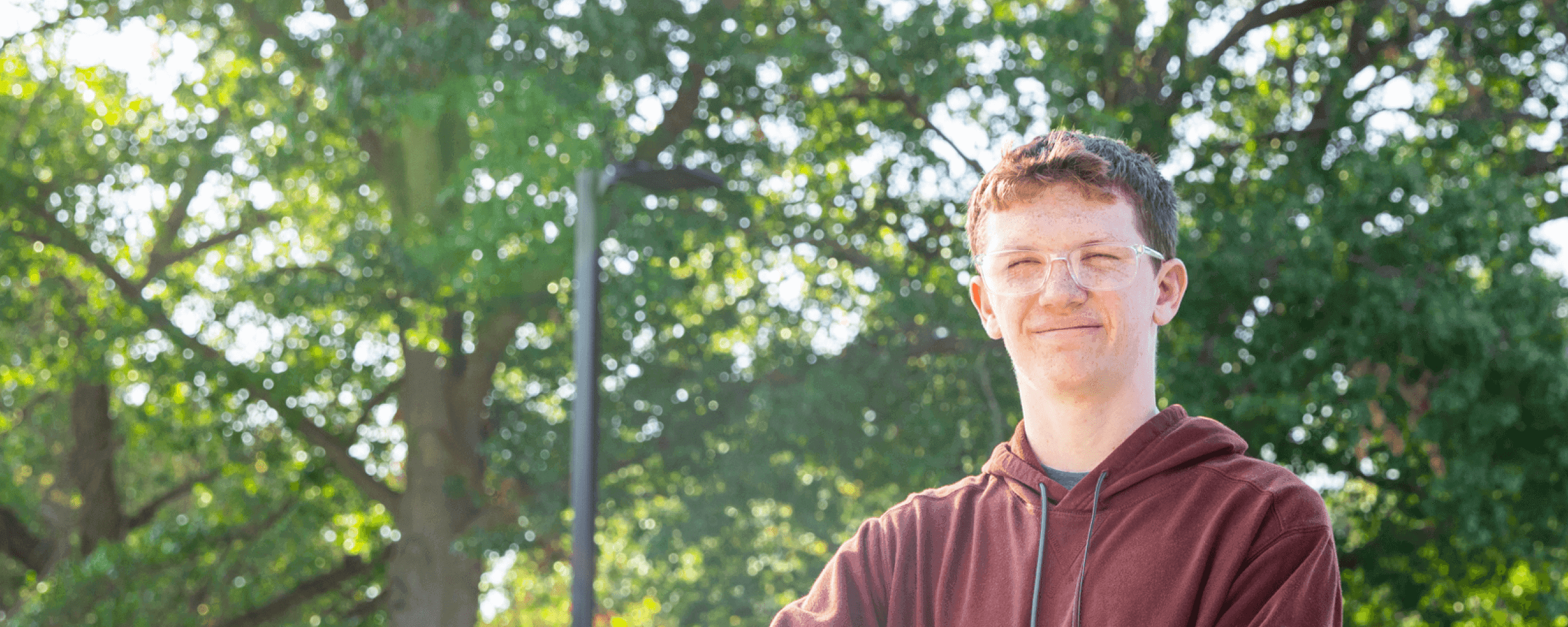 Teen boy standing outside while holding a basketball and looking at the camera